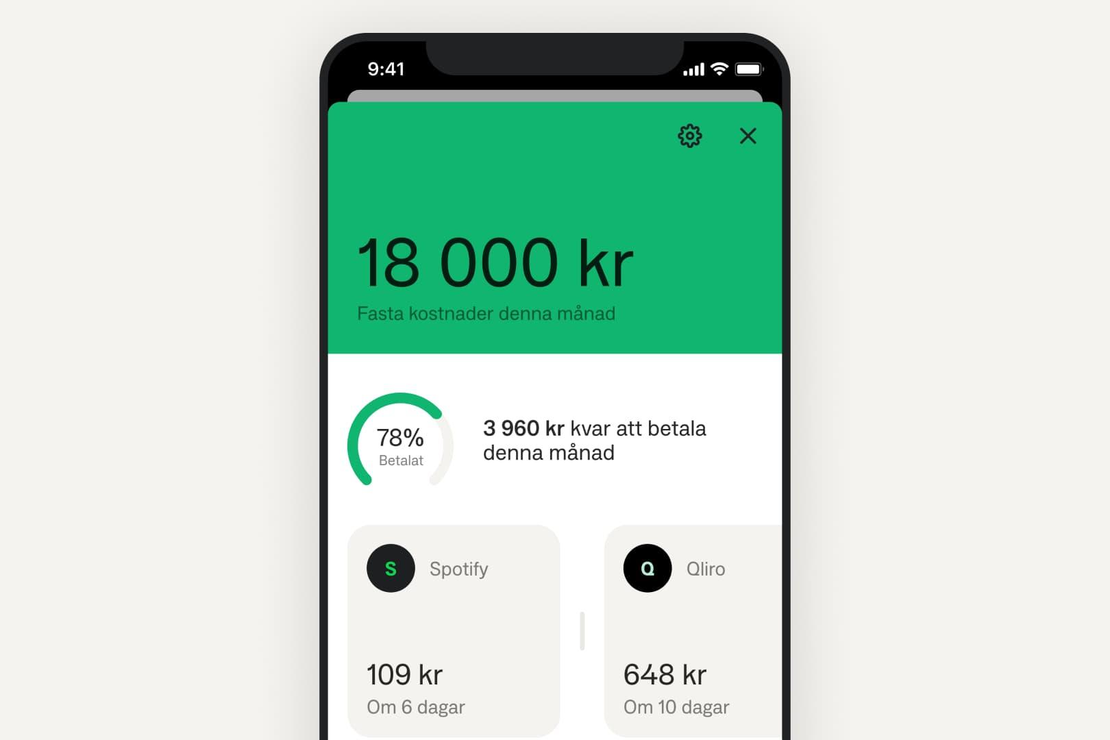 En hand håller i en mobil med Anyfins nya widget. I bakgrunden syns kullersten.