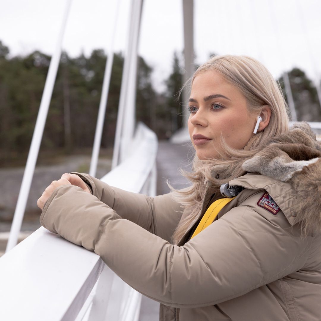 Blonde Frau mit Kopfhörern auf einer Brücke