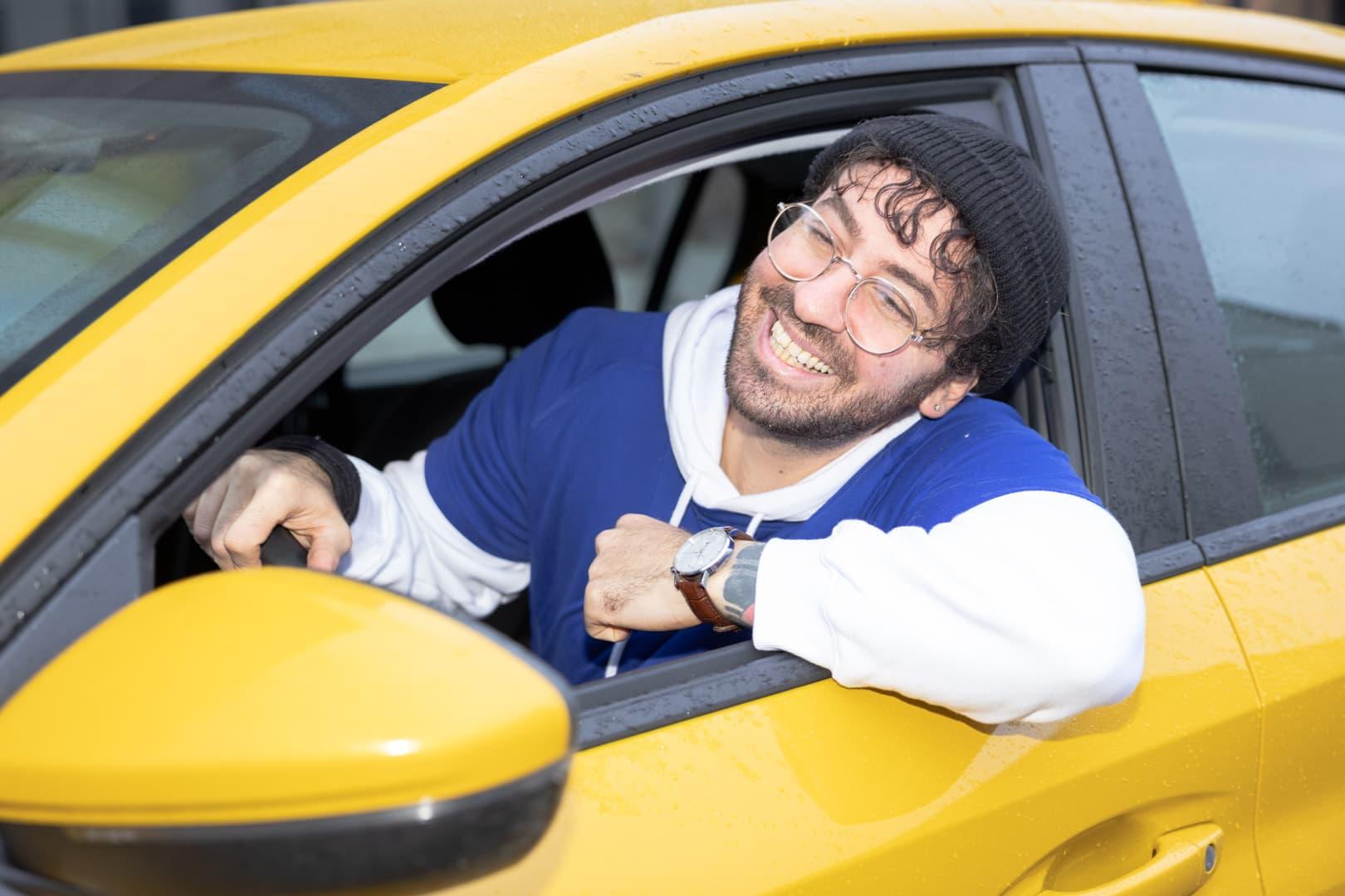 En Anyfinkund som ler i en gul bil.