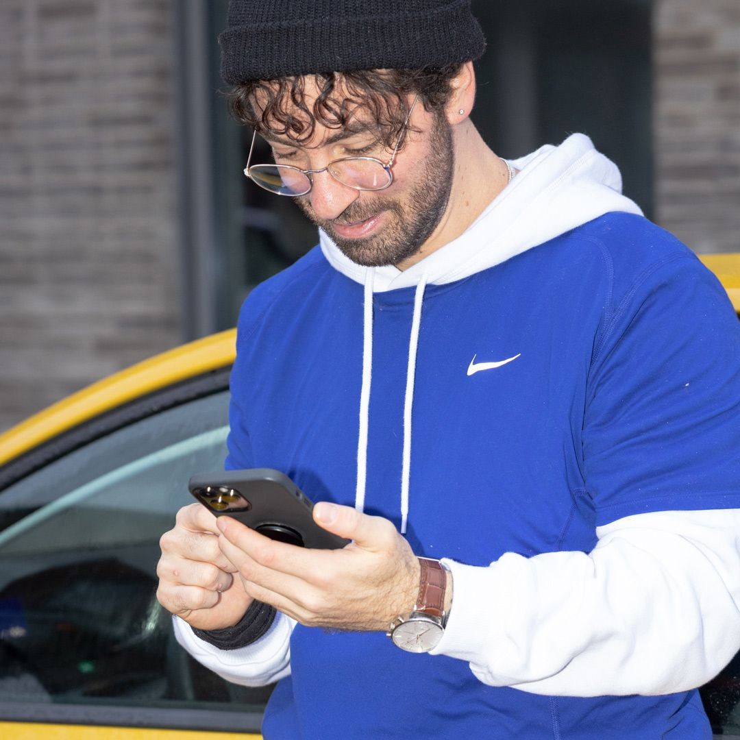 Ein Anyfin-Kunde mit seinem Handy vor seinem Auto