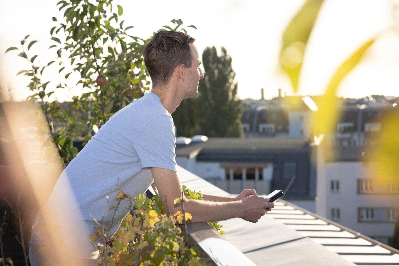 Junger Mann draußen auf dem sonnigen Balkon