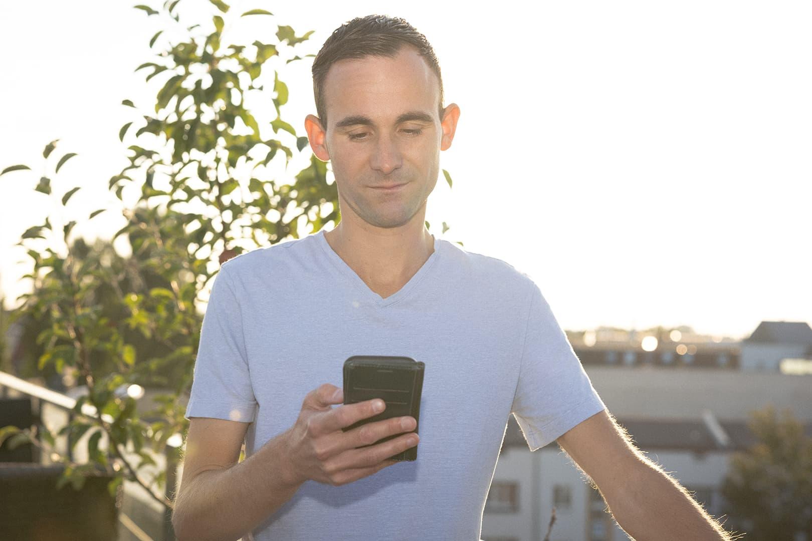 En Anyfinkund står på en balkong i Berlin och tittar ner på sin mobil.