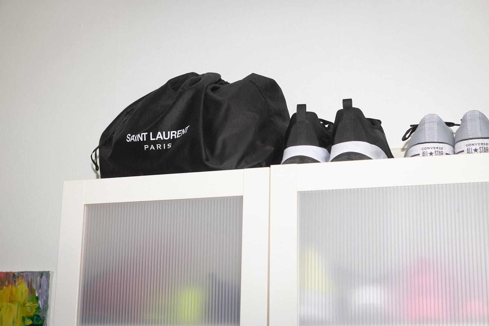 En svart kasse med text på står brevid två par skor ovanpå en garderob.