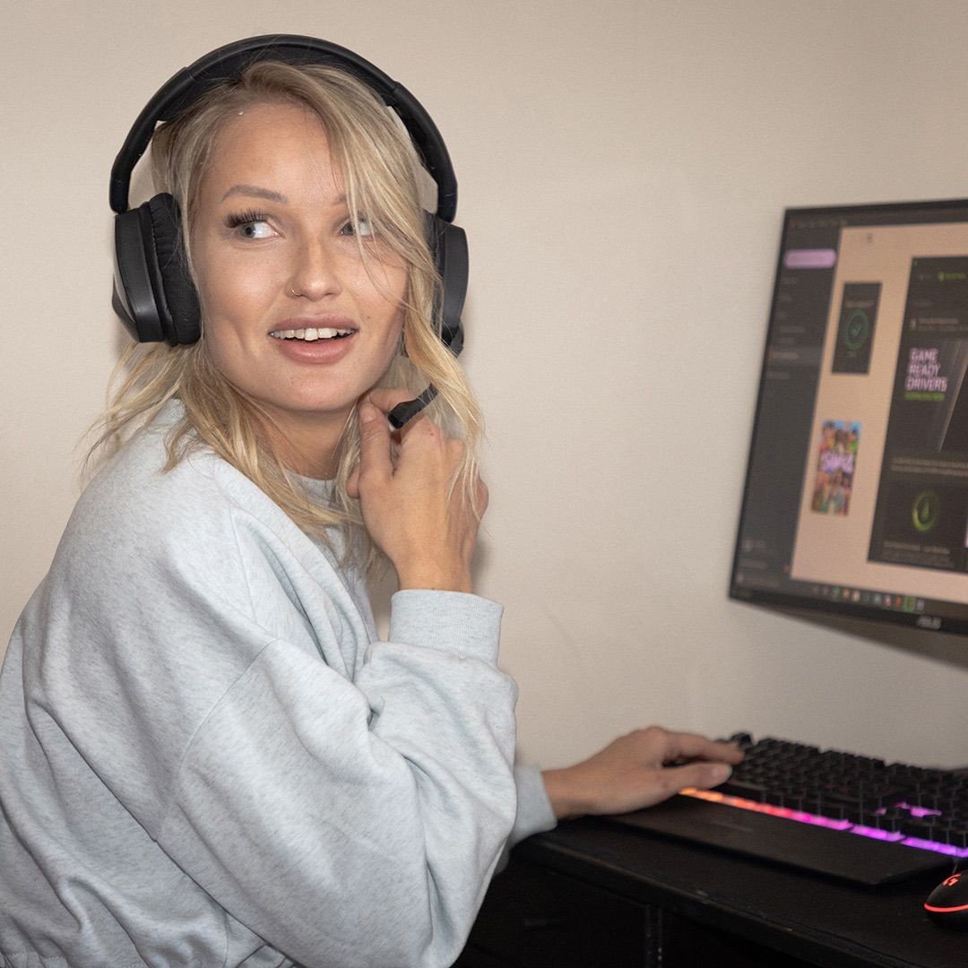 En kvinna med ett headset som sitter vid en dator.