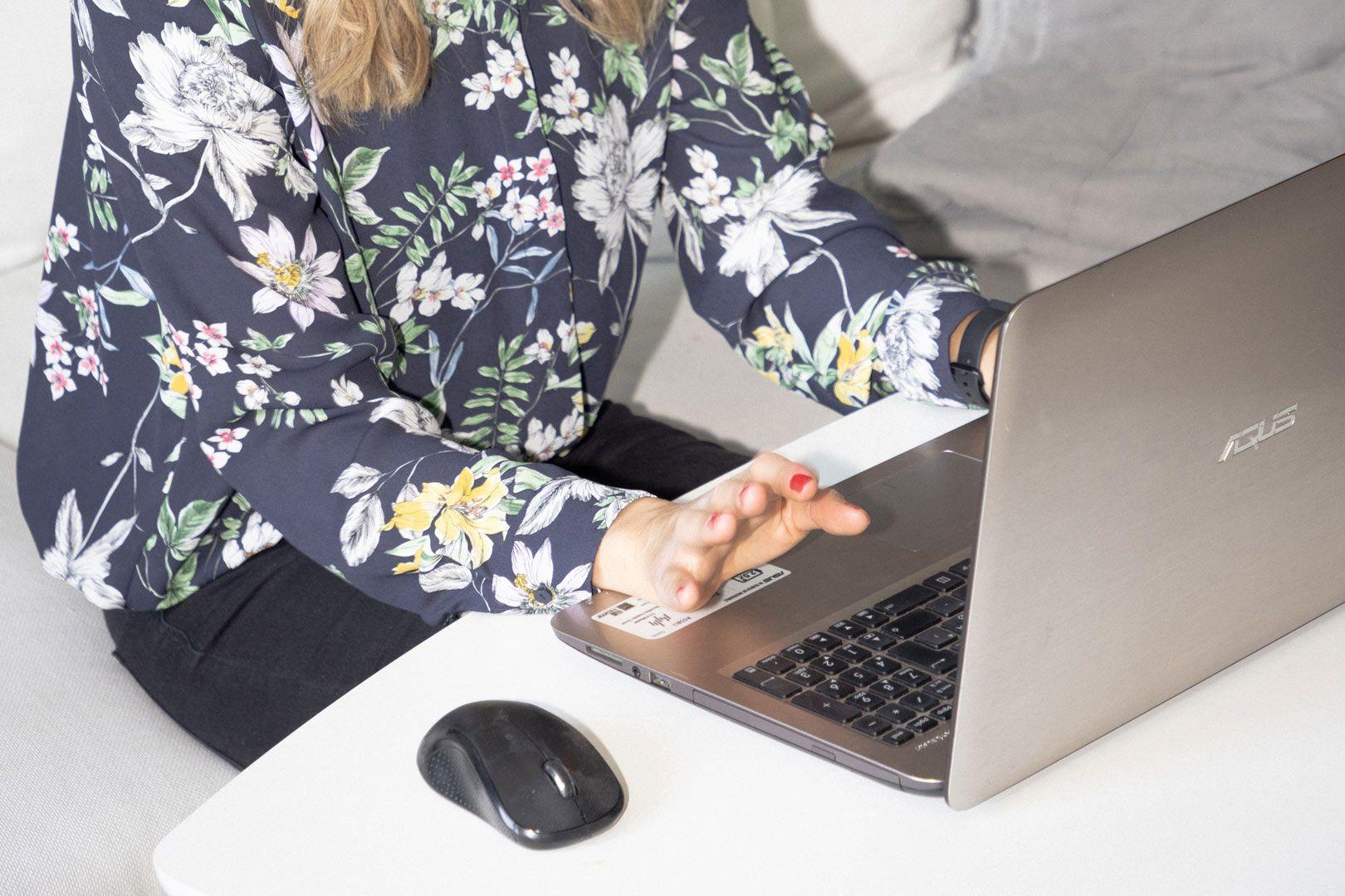Hände einer blonden Frau auf der Tastatur eines Laptops