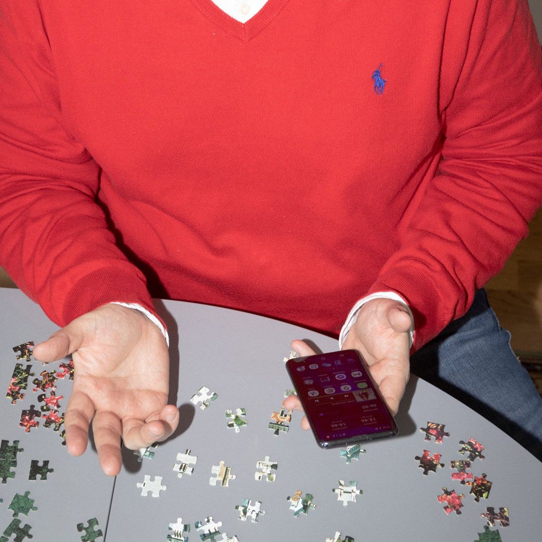 En man med röd tröja som håller i en mobiltelefon.