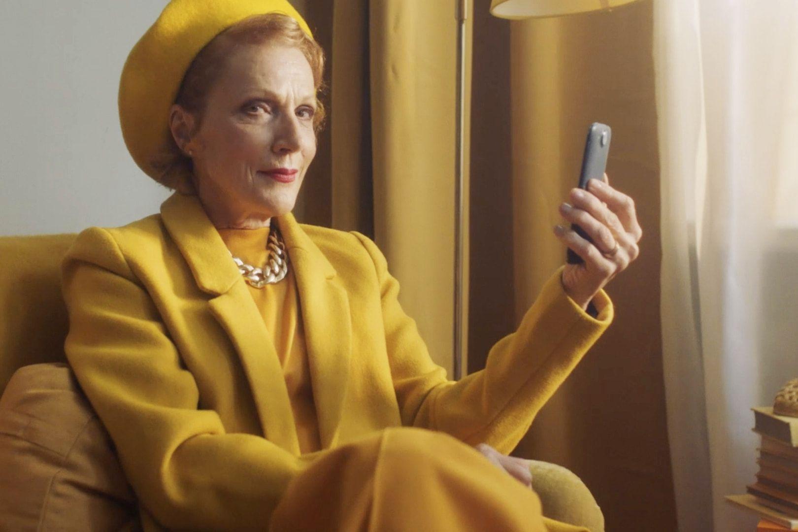 Frau in Gelb mit Handy in der Hand