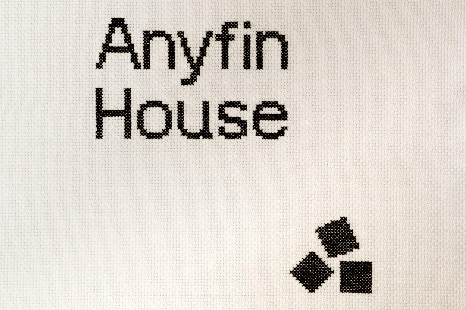 Texten Anyfin House broderat på ett vitt tyg.